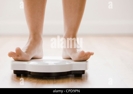 Caucasian woman's feet standing on scale Stock Photo