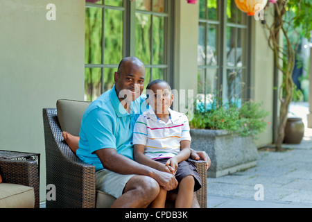 African American father and son sitting on patio Stock Photo