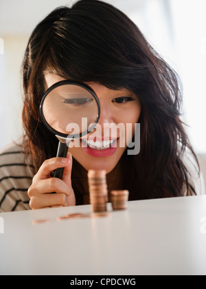 Pacific Islander woman examining pennies with magnifying glass Stock Photo
