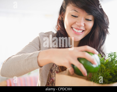 Pacific Islander woman taking groceries from grocery bag Stock Photo