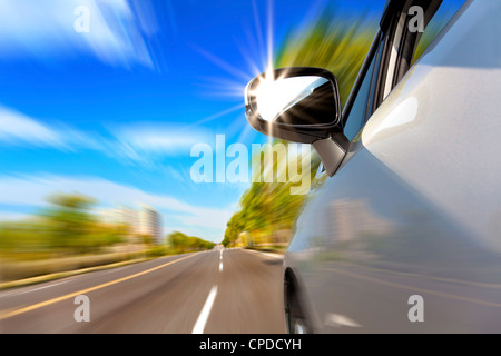 car on the road with motion blur and sunlight in the mirror Stock Photo