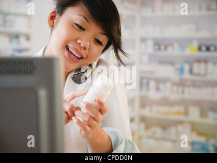 Pacific Islander pharmacist reviewing medication and talking on telephone Stock Photo