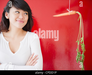 Pacific Islander woman looking at a carrot on a string Stock Photo