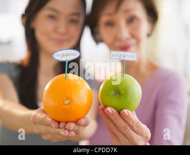 Japanese mother and daughter holding fruit with organic label Stock Photo