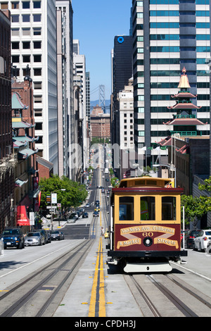 Cable car crossing California Street with Bay Bridge backdrop in San Francisco, California, USA Stock Photo
