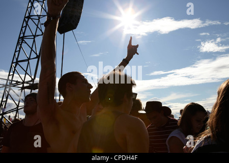 Young people dancing and cheering in the sunshine at a music festival party Stock Photo