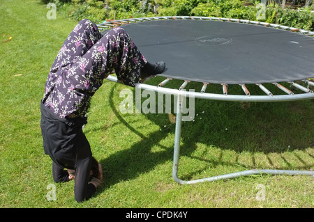 A woman practices yoga using a trampoline Stock Photo