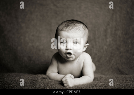 15 week old baby doing tummy time holding herself up. It looks like she's trying to talk. Stock Photo