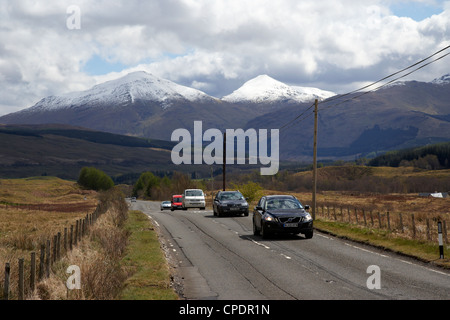 traffic on a82 trunk road through the scottish highlands with snow covered mountains ben more left and stobinian near tyndrum Stock Photo