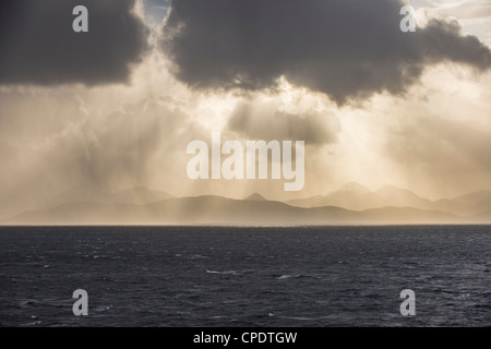Dramatic storm clouds and shafts of sun light over The Cuillin on the Isle of Skye from Applecross, Highlands, Scotland, UK Stock Photo