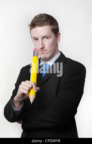 man holding a very large pencil wearing a busniess suit thinking about something Stock Photo