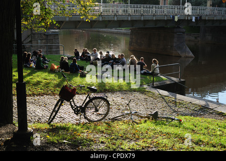 a group of young people talking while sitting on the riverbank, Turku, Finland, 2011 Stock Photo