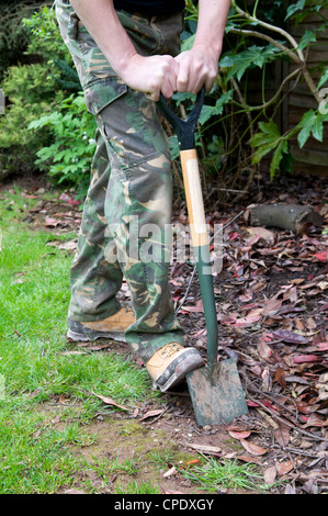 Caucasian man digging out border with garden spade in garden in Bristol, UK Stock Photo