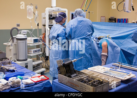 Orthopedic surgeon preparing patient for arthroscopic knee surgery in a hospital operating room suite Stock Photo