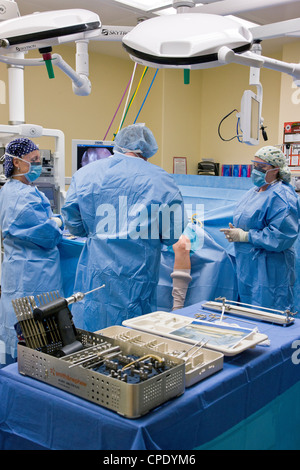 Orthopedic surgeon preparing patient for arthroscopic knee surgery in a hospital operating room suite Stock Photo