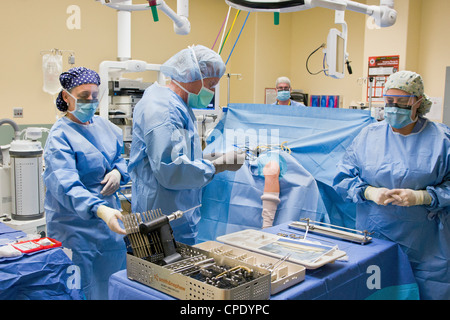 Orthopedic surgeon preparing patient for arthroscopic knee surgery in a hospital operating room suite Stock Photo