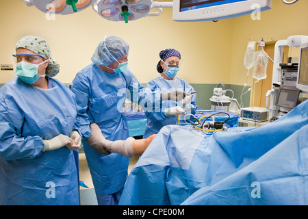 Orthopedic surgeon preparing patient for arthroscopic knee surgery in a hospital operating room suite Stock Photo