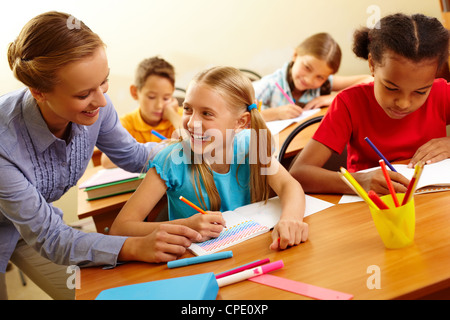 Portrait of smart girl and her teacher looking at each other at lesson in classroom Stock Photo