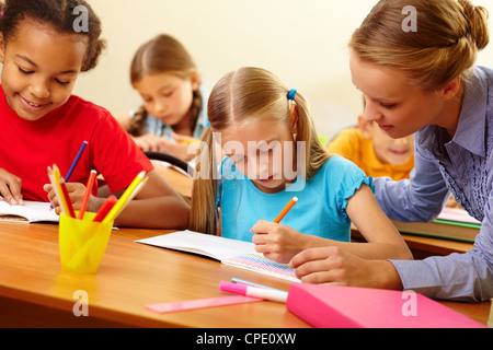 Portrait of teacher looking at a drawing schoolgirl’s copybook at lesson Stock Photo