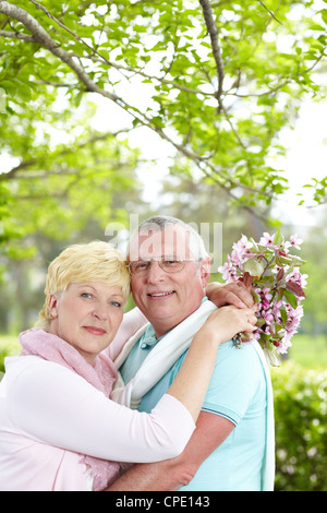 Happy mature couple embracing and looking at camera outside Stock Photo