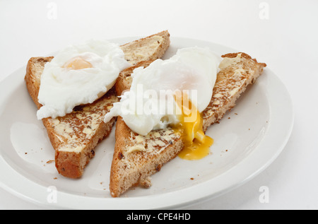 Two soft poached eggs on toast with runny golden yolk Stock Photo