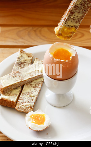 A buttered toast soldiers being dipped into a soft boiled egg in an egg cup Stock Photo