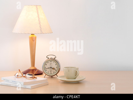 Table Lamp, Teacup, Clock, Spectacles And Books On Table Stock Photo