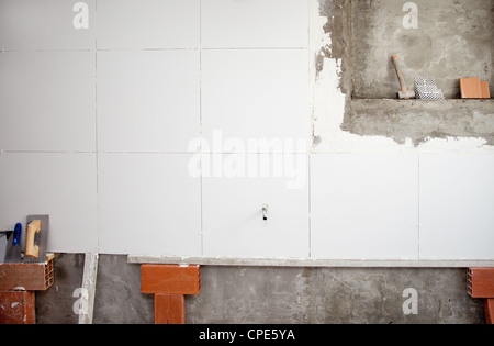 tiles white wall contruction with trowels tools and bricks Stock Photo