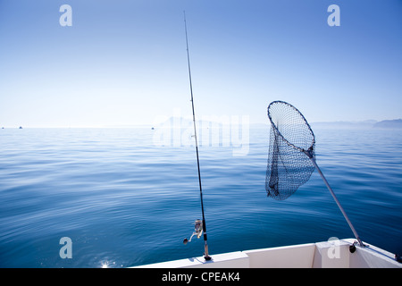 boat fishing rod and landing net in mediterranean blue sea Stock Photo