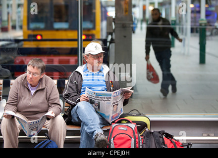 Manchester Piccadilly railway station passengers reading in waiting area Stock Photo