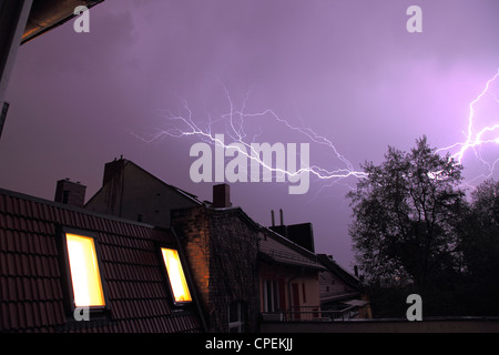 lightning storm with bolts above the rooftops of row houses Stock Photo