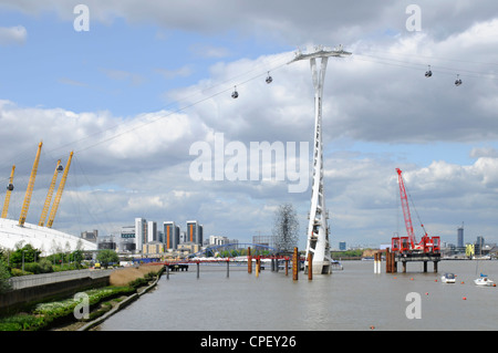 Emirates Air Line cable car gondolas with pylons & cables above River Thames at Greenwich Peninsula adjacent to o2 dome Stock Photo