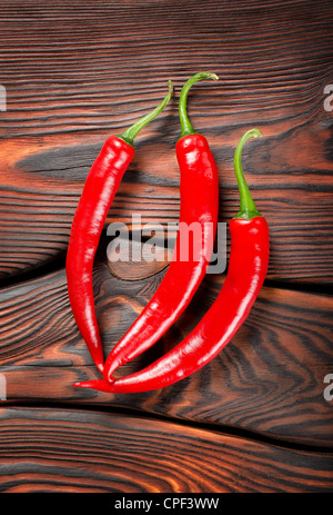 Three red chili peppers on a wooden background Stock Photo