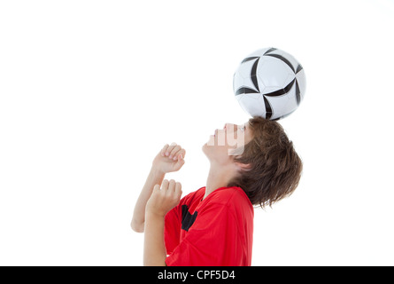 young boy soccer or football player balancing ball on head Stock Photo