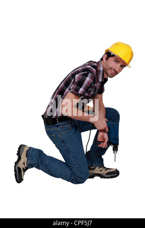 Man kneeling with drill Stock Photo