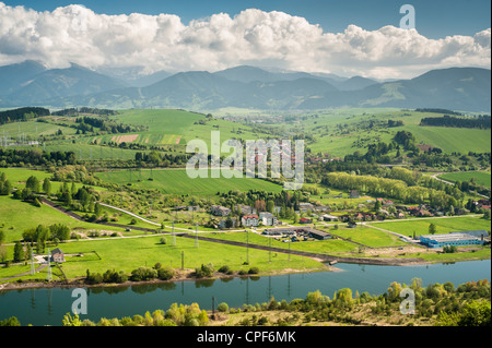 River in a green country with a village, mountains and clouds Stock Photo