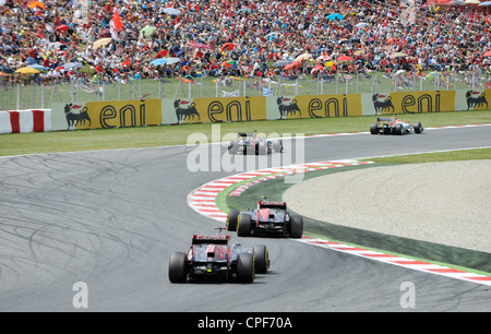 Four race cars pass through curve in front of grandstand filled with ...