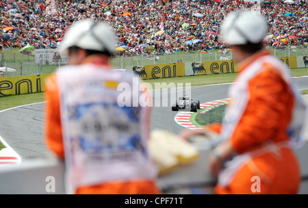 race car passes through curve in front of grandstand filled with ...