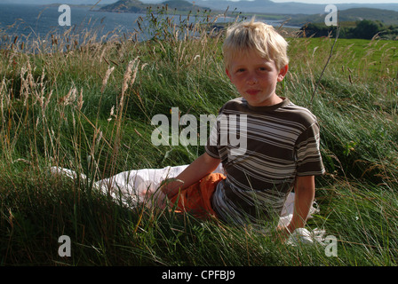 Boy sitting on cliff top, Scotland, UK Stock Photo