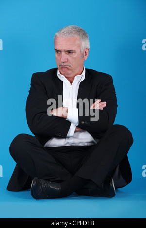 Grumpy man sitting on the floor Stock Photo - Alamy