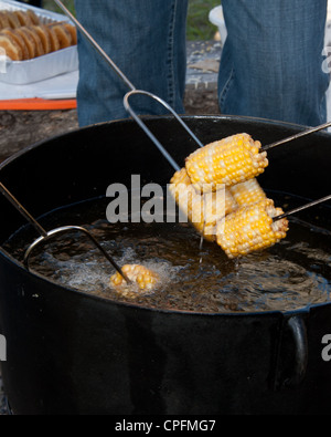 Cooking corn cobs in the pitchfork fondue. Stock Photo