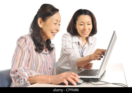 Senior woman using laptop together with mid adult woman Stock Photo