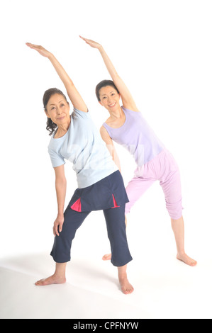 Senior woman and mid adult woman stretching side of bodies Stock Photo