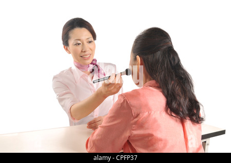 Mid adult woman doing senior woman's makeup Stock Photo