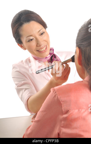 Mid adult woman doing senior woman's makeup Stock Photo