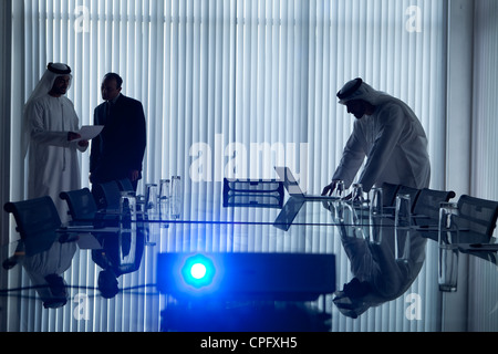 Arab businessman using laptop in his presentation at the conference room with two businessmen holding a document. Stock Photo