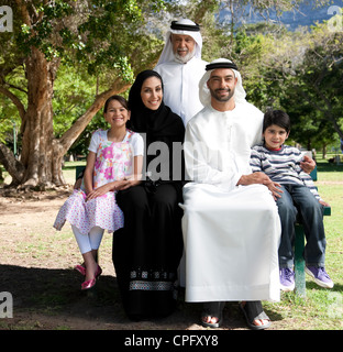 Portrait of multi-generation arab family sitting on bench at the park, smiling. Stock Photo