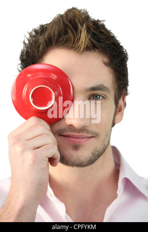 Young man holding a saucer in front of his eye Stock Photo
