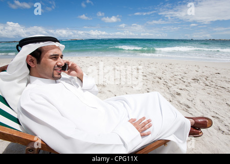 Arab man on the mobile phone sitting at the beach. Stock Photo