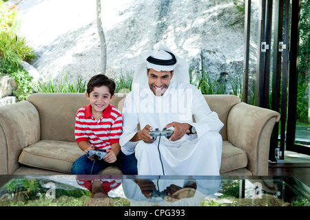 Arab father and son playing video game together. Stock Photo